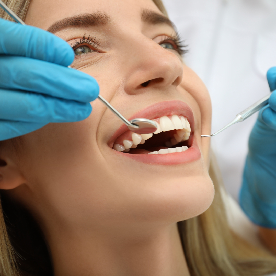 A woman smiles brightly during a teeth evaluation